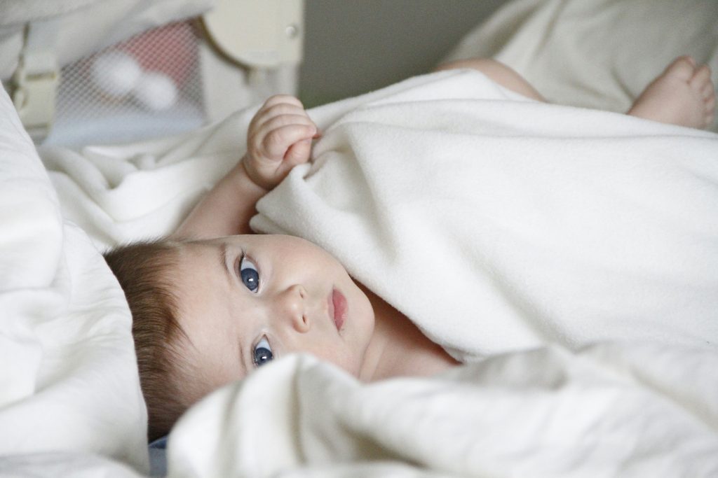 Baby in decke auf einem bett